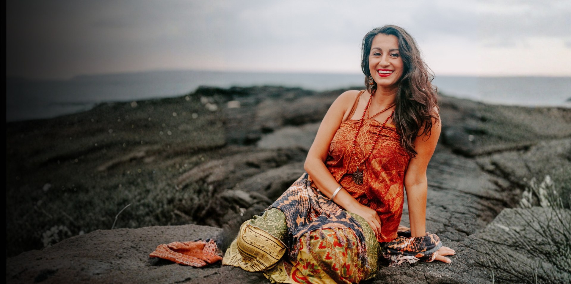 Dr. Rameet Singh seated on a rocky shoreline by the ocean
